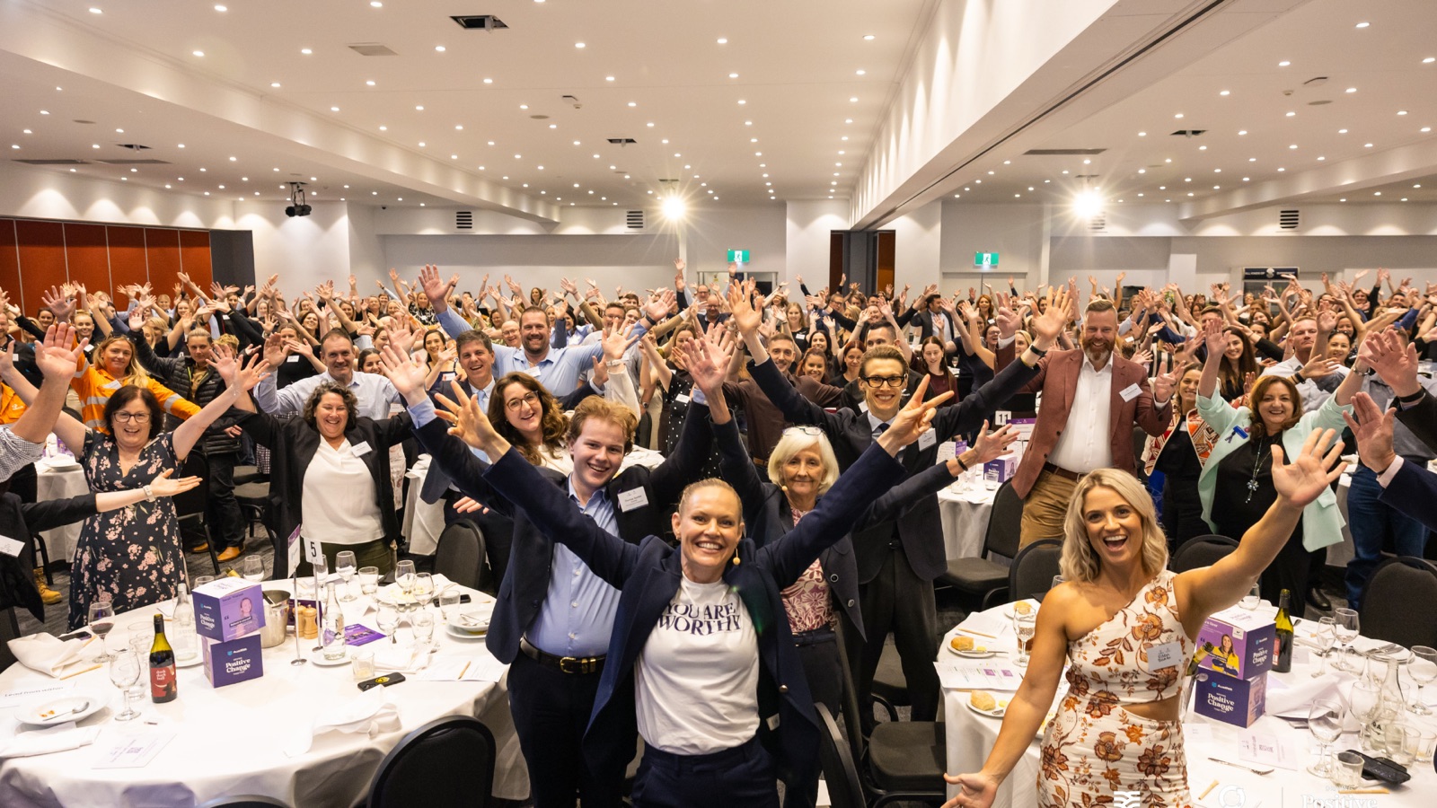 A full room on its feet, arms raised, after a session